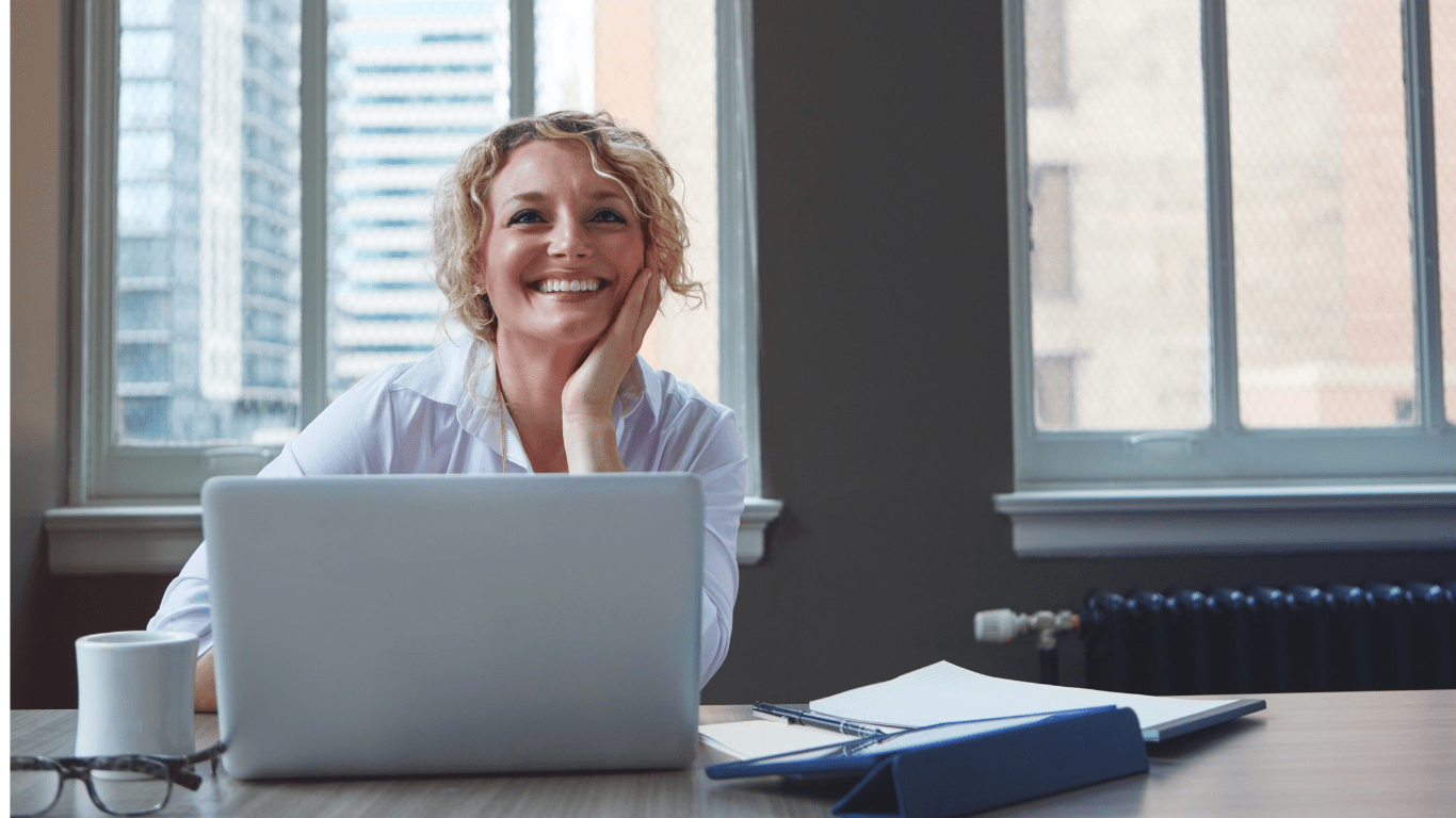 A woman looking happy and hopeful sitting at her computer